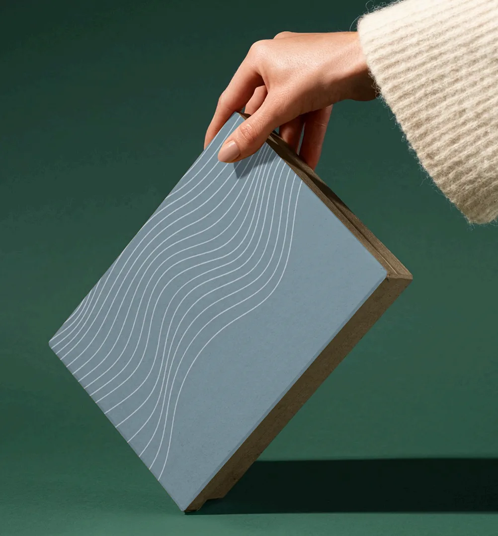 Minimal branded packaging held over a green backdrop